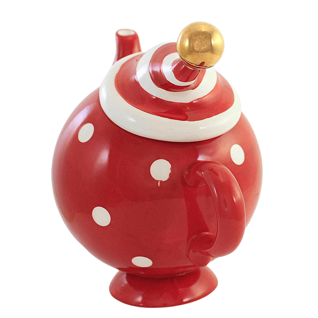 Crop view of female holding porcelain teapot and pouring hot tea into red  ceramic polka-dotted?